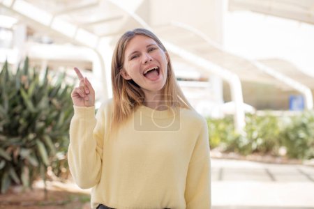 Photo for Pretty young woman feeling like a happy and excited genius after realizing an idea, cheerfully raising finger, eureka! - Royalty Free Image