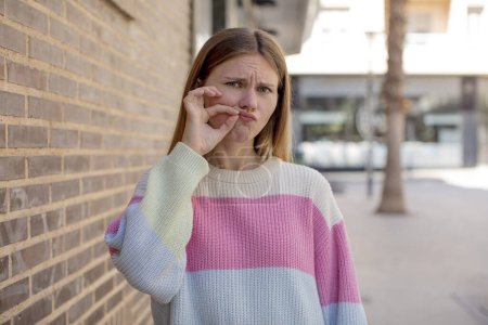 Photo for Pretty young woman looking serious and displeased with both fingers crossed up front in rejection, asking for silence - Royalty Free Image