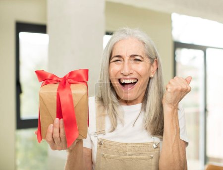 Foto de Mujer mayor sosteniendo una caja de regalo - Imagen libre de derechos