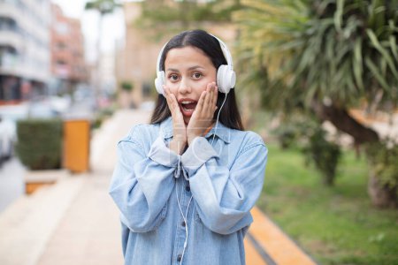 Téléchargez les photos : Hispanique femme écouter de la musique à l'extérieur - en image libre de droit