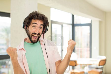 Téléchargez les photos : Jeune homme fou écouter de la musique avec des écouteurs - en image libre de droit