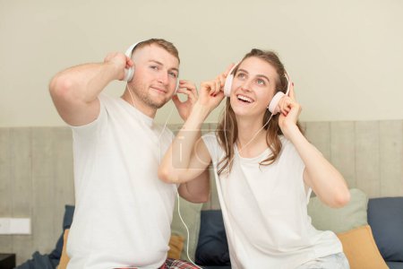 Téléchargez les photos : Jeune couple caucasien écouter de la musique avec écouteurs - en image libre de droit