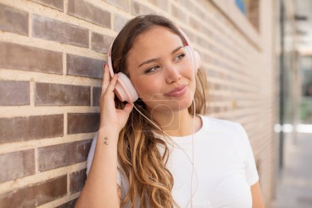 Foto de Mujer bonita hispana escuchando música con auriculares - Imagen libre de derechos