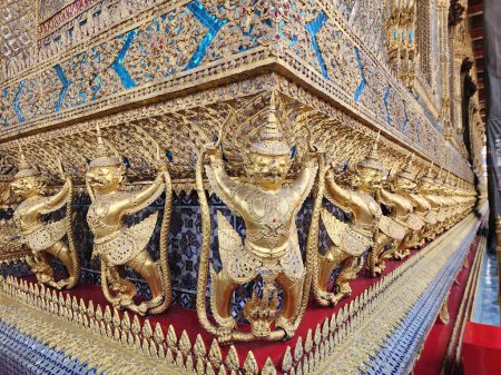 Photo for Garuda figures cast in bronze and gilded with 112 figures lined up around the base of the temple wall, Wat Phra Kaew, Bangkok, Thailand. - Royalty Free Image