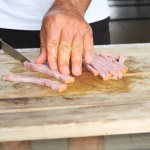 man cutting pork on wooden board