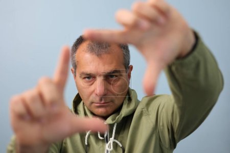 Téléchargez les photos : Visage de l'homme au milieu de ses doigts avec ses mains - en image libre de droit