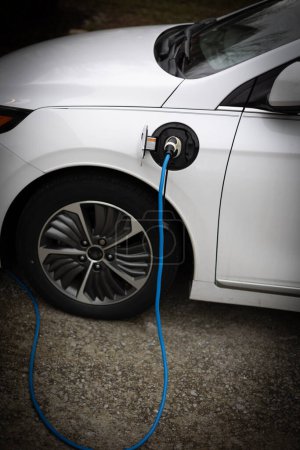 Foto de Un coche eléctrico enchufable se está cargando utilizando un cable de carga de nivel 1 en la entrada de una residencia. - Imagen libre de derechos