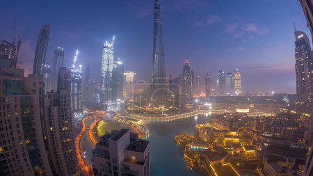 Téléchargez les photos : Vue aérienne de la ville de Dubaï tôt le matin pendant la nuit de brouillard au timelapse de transition de jour. Skyline futuriste de la ville avec des gratte-ciels et des tours au lever du soleil d'en haut - en image libre de droit