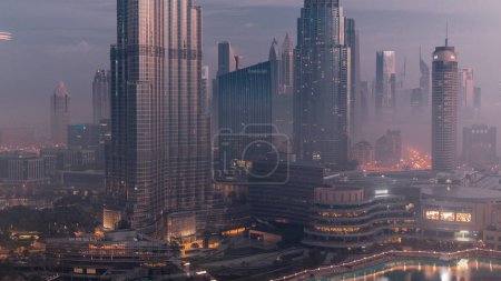 Téléchargez les photos : Vue aérienne de la ville de Dubaï tôt le matin pendant la nuit de brouillard au timelapse de transition de jour. Skyline futuriste de la ville avec des gratte-ciels et des tours d'en haut - en image libre de droit