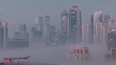 Téléchargez les photos : Les gratte-ciel de Dubaï avec brouillard matinal dans le quartier des affaires nuit à jour passage timelapse. Vue aérienne depuis le haut du centre-ville aux Émirats arabes unis. - en image libre de droit