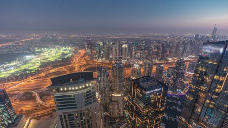 Téléchargez les photos : Panorama de Dubai Marina avec gratte-ciel JLT et parcours de golf de jour comme de nuit timelapse transition, Dubaï, Émirats arabes unis. Vue aérienne depuis les tours supérieures après le coucher du soleil - en image libre de droit