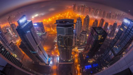 Photo for Rare early morning winter fog during sunrise above the Dubai Marina and JLT skyline and skyscrapers lighted by street lights aerial night to day transition timelapse. Top view from above clouds. Dubai, UAE - Royalty Free Image