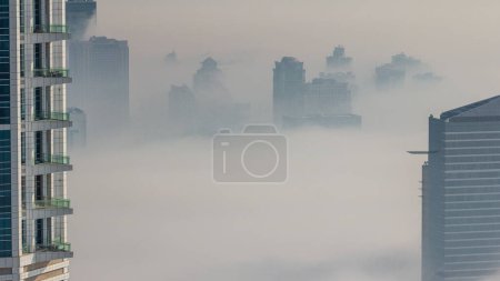 Photo for Dubai Aerial view showing fog over al barsha heights and greens district area timelapse from Dubai marina. Towers and skyscrapers foggy morning from above - Royalty Free Image