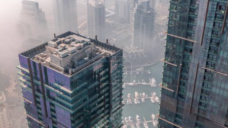 Photo for Top view with modern skyscrapers aerial timelapse and water pier of Dubai Marina with morning haze, United Arab Emirates. Yachts and boats between glass towers - Royalty Free Image