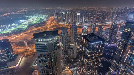 Photo for Panorama of Dubai Marina with JLT skyscrapers and golf course night timelapse, Dubai, United Arab Emirates. Aerial view from above towers. City lights illumination - Royalty Free Image