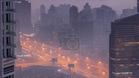 Photo for Dubai aerial view showing al barsha heights and greens district area night to day transition timelapse from Dubai marina. Illuminated towers and skyscrapers before sunrise with traffic on a highway from above - Royalty Free Image