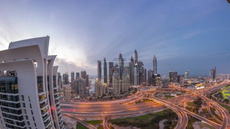 Photo for Panorama of Dubai Marina after sunset highway intersection spaghetti junction day to night transition timelapse. Illuminated tallest skyscrapers on a background. Aerial top view from JLT district. - Royalty Free Image