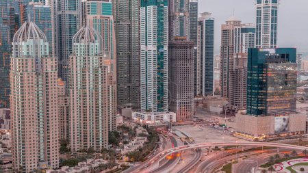 Téléchargez les photos : Les gratte-ciel de Dubai Marina avec les bâtiments résidentiels les plus lumineux du jour au soir après le coucher du soleil. Vue aérienne du quartier JLT avec intersection de l'autoroute - en image libre de droit