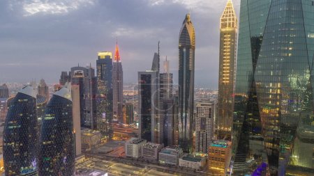 Téléchargez les photos : Centre financier de la ville de Dubaï avec des gratte-ciel de luxe jour à nuit transition timelapse, Dubaï, Émirats arabes unis. Vue aérienne avec parking et tours sur les toits - en image libre de droit