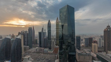Téléchargez les photos : Coucher de soleil sur le centre financier de Dubaï avec des gratte-ciel de luxe timelapse, Dubaï, Émirats arabes unis. Vue panoramique aérienne avec ciel orange et tours autour d'un grand parking - en image libre de droit