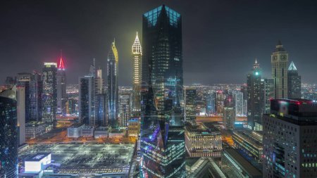 Photo for Panorama showing futuristic skyscrapers in financial district business center in Dubai on Sheikh Zayed road night timelapse. Aerial view from above with illuminated towers - Royalty Free Image