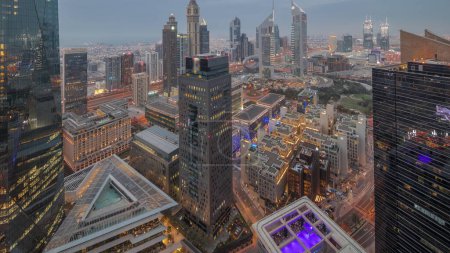 Foto de Panorama de rascacielos futuristas después del atardecer en el centro de negocios del distrito financiero en Dubai en el camino Sheikh Zayed día a noche timelapse transición. Vista aérea desde arriba con museo - Imagen libre de derechos