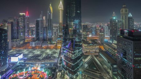 Photo for Panorama showing futuristic skyscrapers in financial district business center in Dubai on Sheikh Zayed road night timelapse. Aerial view from above with illuminated towers - Royalty Free Image