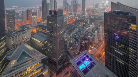 Foto de Panorama de rascacielos futuristas en el centro de negocios del distrito financiero en Dubai en el camino Sheikh Zayed noche a día timelapse transición. Vista aérea desde arriba con torres iluminadas antes del amanecer - Imagen libre de derechos