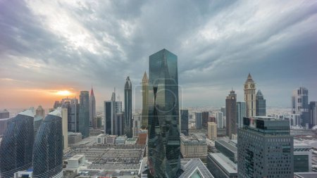 Photo for Panorama of futuristic skyscrapers with sunset in financial district business center in Dubai on Sheikh Zayed road timelapse. Aerial view from above with colorful cloudy sky - Royalty Free Image