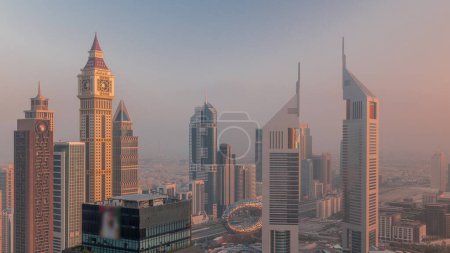 Photo for Skyscrapers on Sheikh Zayed Road and DIFC morning timelapse in Dubai, UAE. Towers in financial centre aerial view from above. Warm orange light during sunrise - Royalty Free Image