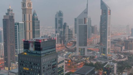 Téléchargez les photos : Des gratte-ciel sur Sheikh Zayed Road et DIFC nuit à jour passage timelapse à Dubaï, EAU. Tours lumineuses dans le centre financier vue aérienne d'en haut. Météo brumeuse avant le lever du soleil - en image libre de droit