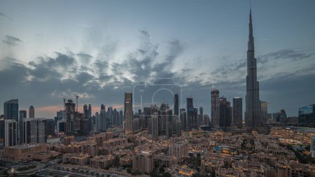 Photo for Dubai Downtown panorama day to night transition timelapse with tallest skyscraper and other towers view from the top after sunset in Dubai, United Arab Emirates. Lights turning on. - Royalty Free Image