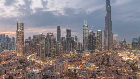 Téléchargez les photos : Dubaï Temps de transition du jour à la nuit au centre-ville avec le plus haut gratte-ciel et d'autres tours autour de la vieille ville vue du haut après le coucher du soleil à Dubaï, Émirats arabes unis. Lumières allumées. - en image libre de droit