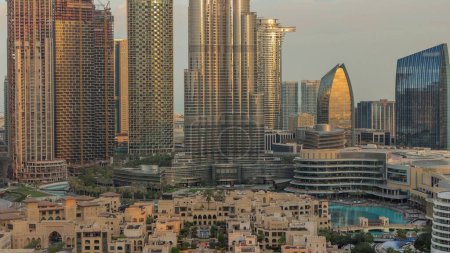 Photo for Dubai Downtown morning timelapse with sun reflected from tallest skyscraper and other towers view from the top during sunrise, United Arab Emirates. Traditional houses of old town - Royalty Free Image