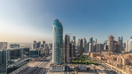 Foto de Panorama que muestra la bahía de negocios de Dubái y el timelapse de las torres del centro de la ciudad. Vista en la azotea de algunos rascacielos y edificios nuevos en construcción con casas de tadición del casco antiguo - Imagen libre de derechos