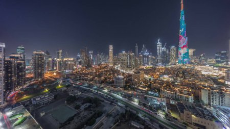 Foto de Dubai Downtown timelapse panorámico nocturno con rascacielos más altos y otras torres iluminadas vista desde la parte superior en Dubai, Emiratos Árabes Unidos. Casas tradicionales del casco antiguo - Imagen libre de derechos