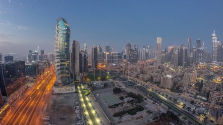 Photo for Panorama of Dubai's business bay towers aerial night to day transition timelapse. Rooftop view of some skyscrapers and new buildings under construction before sunrise - Royalty Free Image