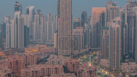 Foto de Paisaje urbano aéreo futurista noche a día timelapse transición con arquitectura iluminada del centro de Dubai y la bahía de negocios. Rascacielos altos y torres. Nuevo sitio de construcción. - Imagen libre de derechos