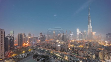 Téléchargez les photos : Dubaï Timelapse de transition du centre-ville de nuit au jour avec le soleil reflété par le plus haut gratte-ciel et d'autres tours avec une vue ombragée du haut pendant le lever du soleil, Émirats arabes unis. Maisons traditionnelles de la vieille ville - en image libre de droit