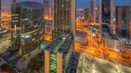 Foto de Dubai centro financiero internacional rascacielos aéreos noche al día timelapse transición. Torres iluminadas con vistas panorámicas al aparcamiento desde arriba antes del amanecer - Imagen libre de derechos