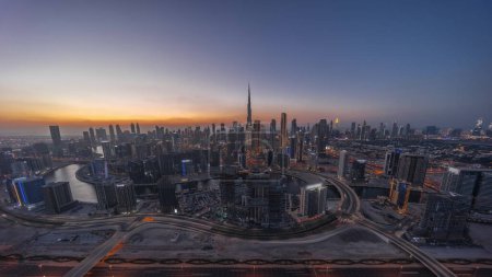 Téléchargez les photos : Skyline panoramique de Dubaï avec baie d'affaires et centre-ville de jour comme de nuit timelapse. Vue aérienne de nombreux gratte-ciel modernes avec circulation sur la route al khail après le coucher du soleil. Émirats arabes unis. - en image libre de droit