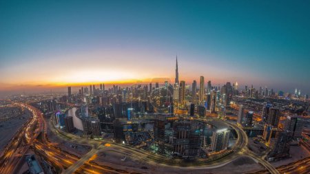 Foto de Skyline panorámico de Dubai con bahía de negocios y el centro de distrito de día a la noche timelapse. Vista aérea de gran angular de muchos rascacielos modernos con tráfico en la carretera al khail después del atardecer. - Imagen libre de derechos
