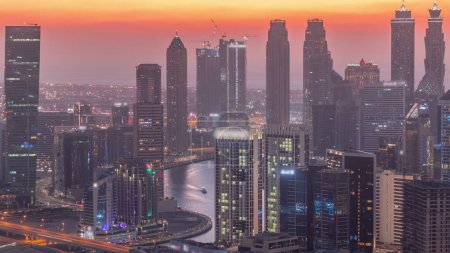 Foto de Skyline con la arquitectura moderna de Dubai torres de la bahía de negocios día a noche timelapse transición. Vista aérea con canal y sitio de construcción después del atardecer con cielo colorido - Imagen libre de derechos