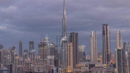 Foto de Skyline panorámica del distrito de Dubai centro con la bahía de negocios noche a día timelapse transición. Vista aérea de muchos rascacielos modernos antes del amanecer. Emiratos Árabes Unidos. - Imagen libre de derechos