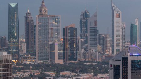 Téléchargez les photos : Rangées de gratte-ciel dans le quartier financier de Dubaï ciel nuit à jour passage timelapse. Vue panoramique sur de nombreuses tours éclairées du quartier Business Bay avant le lever du soleil - en image libre de droit