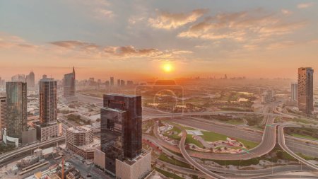 Téléchargez les photos : Lever du soleil sur la jonction de l'autoroute près de la ville des médias et al Barsha hauteurs quartier zone sur un timelapse de fond de la marina de Dubaï. Tours et gratte-ciel tôt le matin avec terrain de golf et la circulation sur une autoroute d'en haut - en image libre de droit