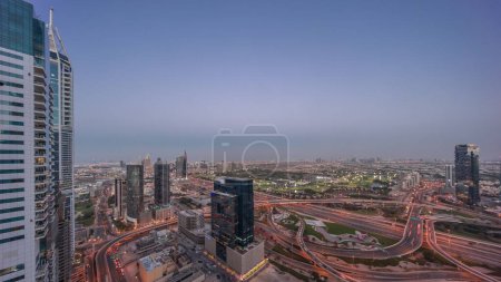 Foto de Vista panorámica aérea de la ciudad de los medios de comunicación y las alturas de al barsha zona del distrito día a la noche timelapse transición desde el puerto deportivo de Dubai. Torres y rascacielos con tráfico en una carretera desde arriba - Imagen libre de derechos