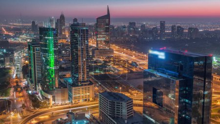 Téléchargez les photos : Vue aérienne de la ville des médias et de la zone du quartier des hauteurs al barsha nuit à jour passage timelapse de la marina de Dubaï. Tours et gratte-ciel avec circulation sur une autoroute par le haut - en image libre de droit