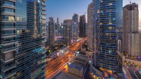 Téléchargez les photos : Vue panoramique sur la marina de Dubaï et la zone JBR timelapse de transition du jour à la nuit. Trafic sur la route après le coucher du soleil - en image libre de droit