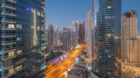 Téléchargez les photos : Vue sur la marina de Dubaï et le quartier de JBR et la circulation sur la route aérienne nuit à jour transition timelapse et gratte-ciel éclairés avant le lever du soleil - en image libre de droit